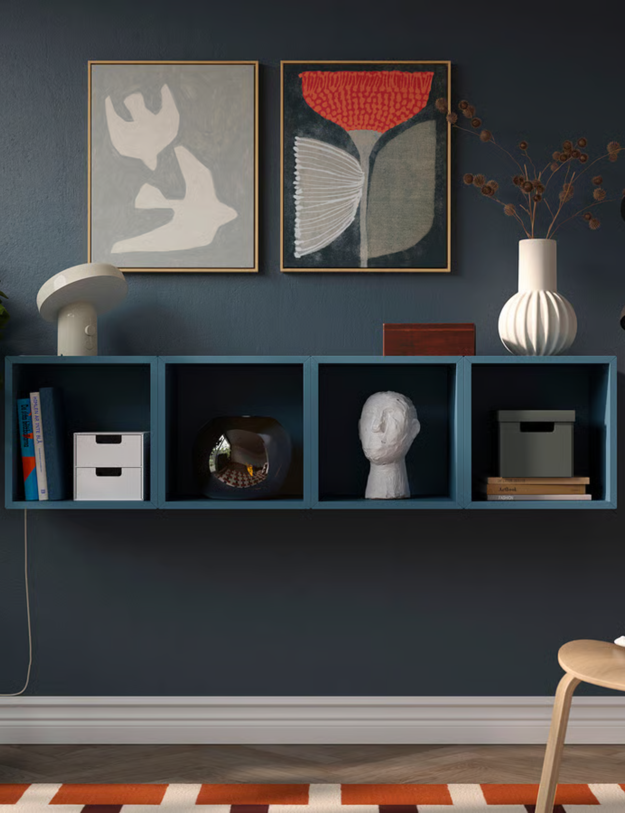 Blue IKEA wall mounted shelf styled with assorted objects in a navy room grounded by a geometric orange rug