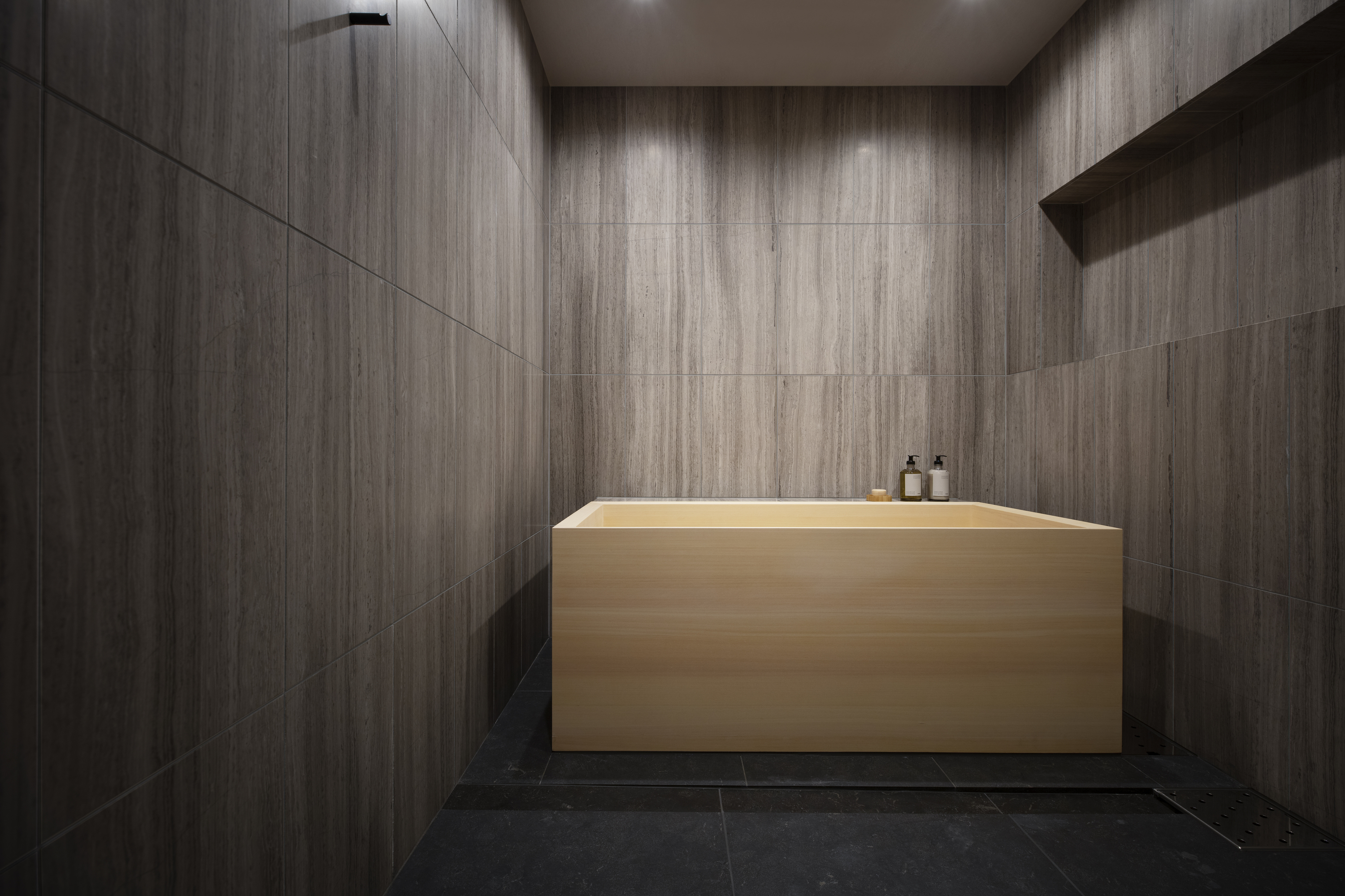 A bathroom with dark walls and a wooden, custom bathtub