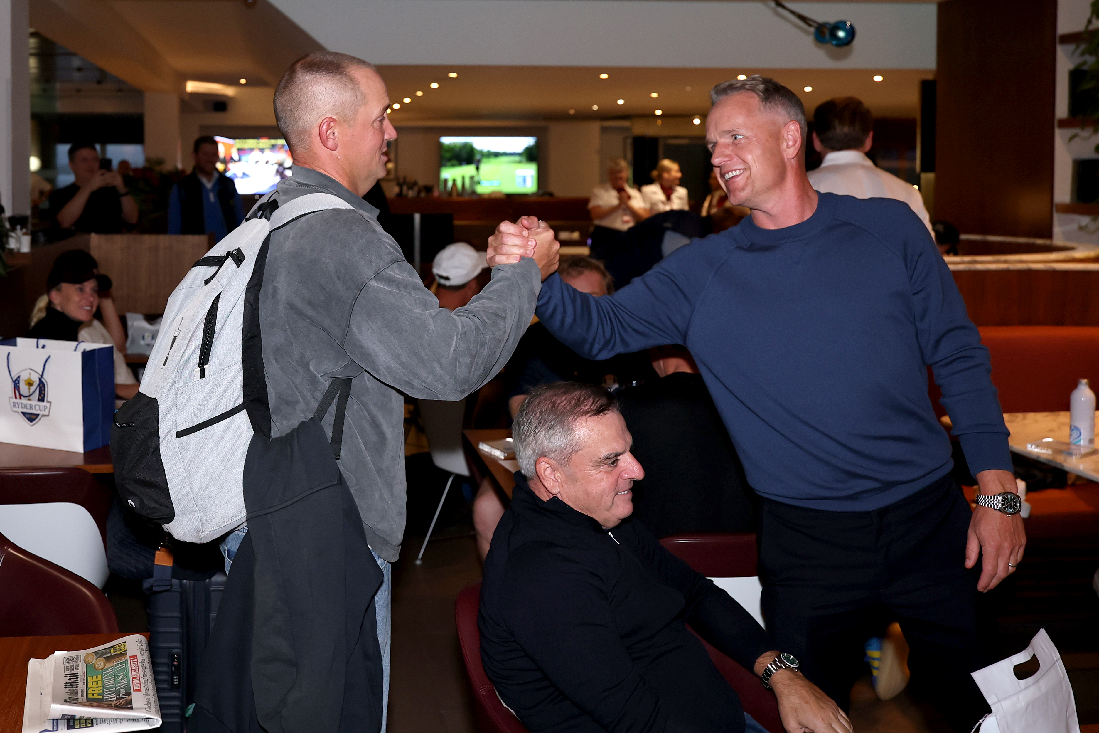 Alex Noren and Luke Donald shake hands at the airport ahead of the European Ryder Cup team&#039;s flight to New York