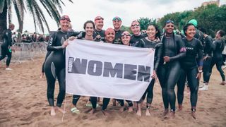 Donna McConnell standing in a group of women all wearing wetsuits holding a 10ironwomen banner