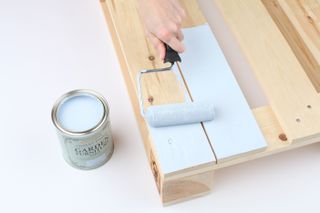 a pallet being painted with a roller brush and light blue outdoor paint