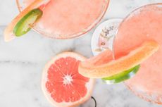 Two pink Paloma cocktails with slices of grapefruit and lime
