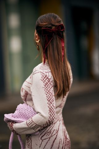 woman with a red and white dress and red velvet bow in her hair facing away from the camera