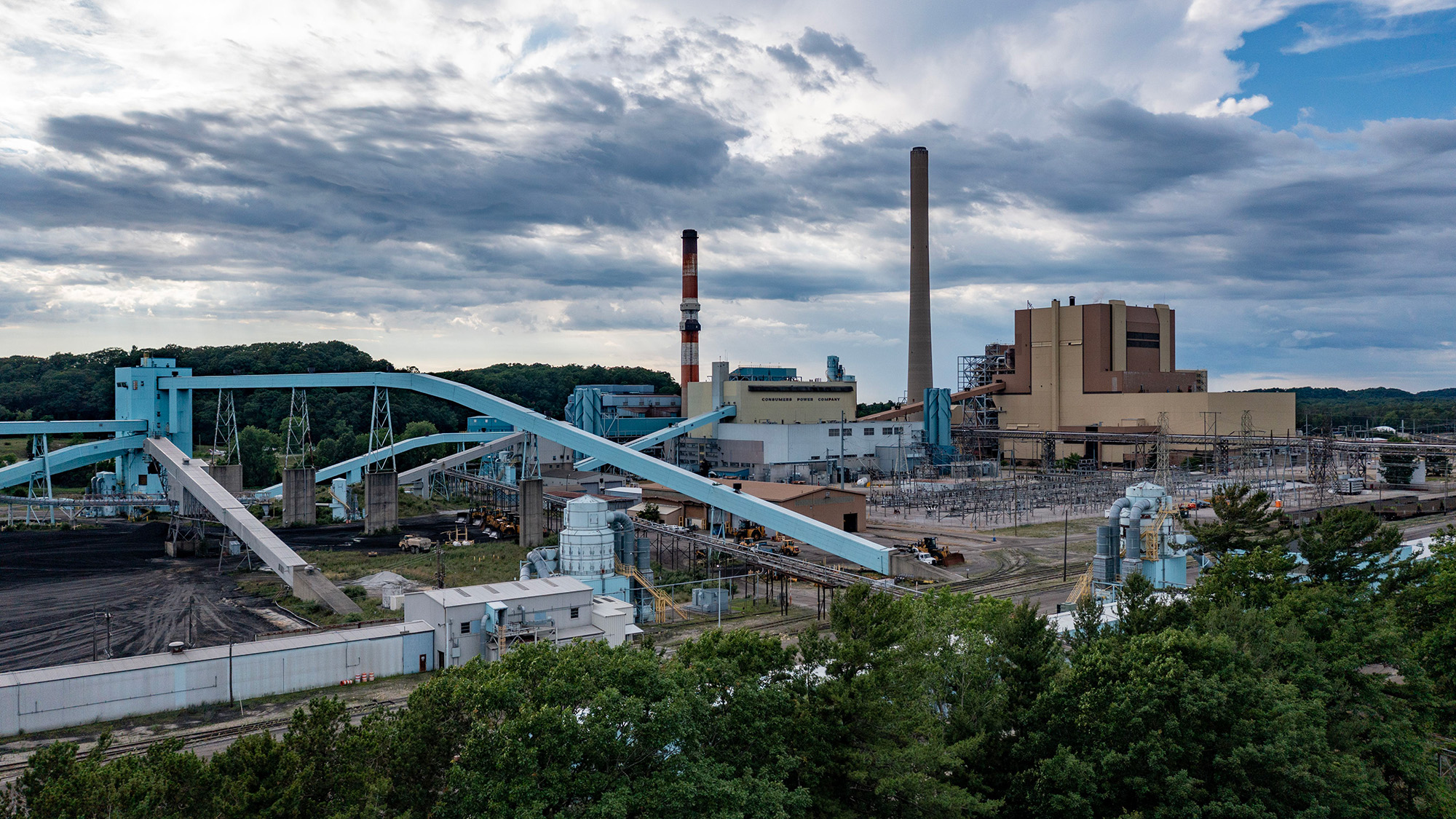 An oil refinery showing several large pipes next to a factory