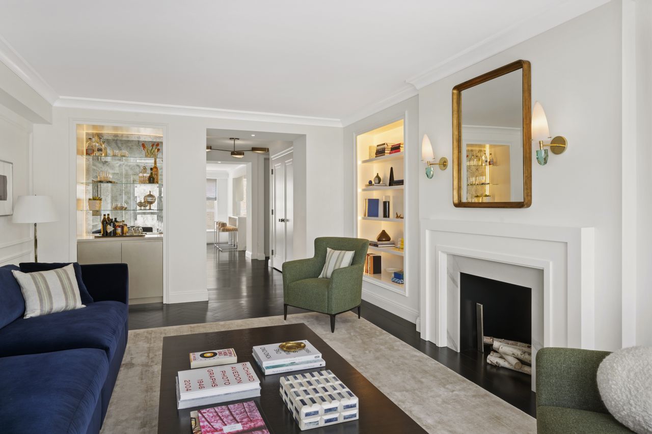 A modern living room with a built in alcove bookcase and a large fireplace