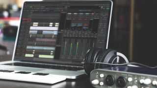 A home studio setup with laptop, audio interface, and headphones