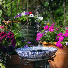Garden water feature made from a container and a solar powered floating water fountain