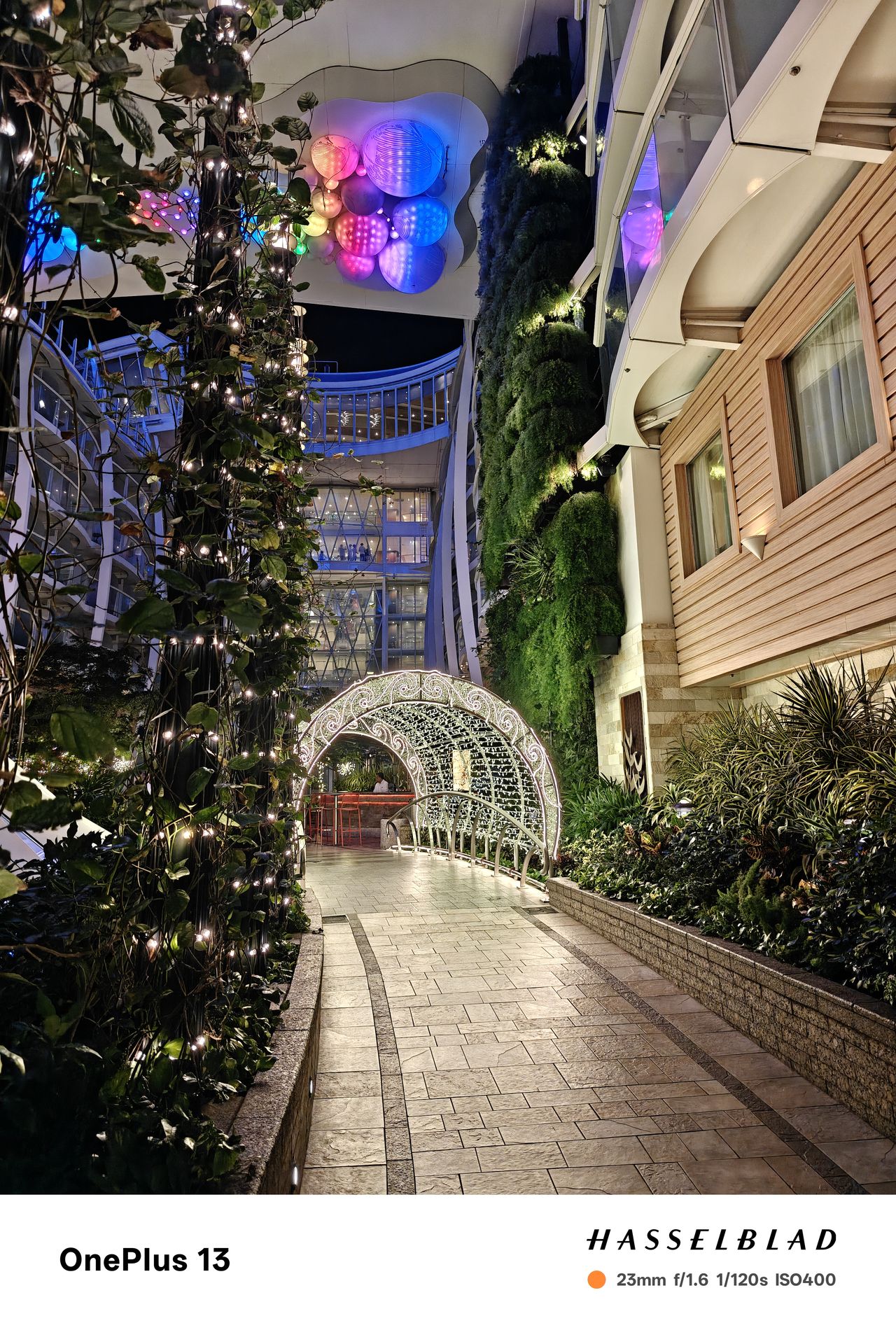 A street leading to a tunnel lit up at night with colorful lights above