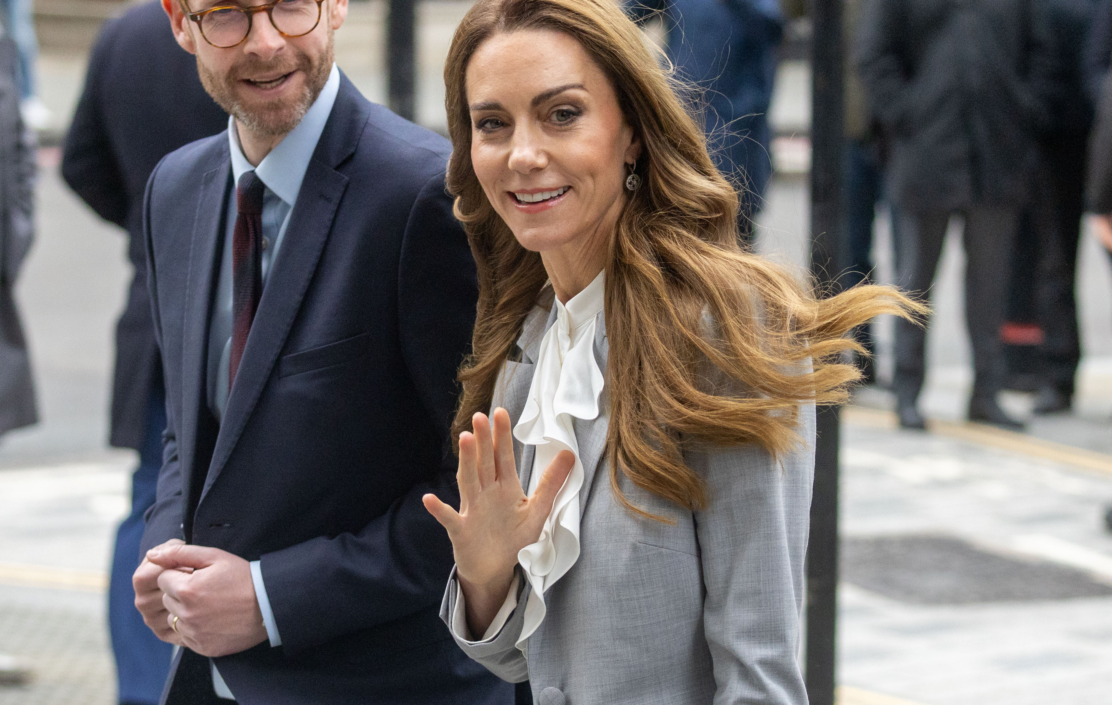 Kate Middleton wearing a gray suit and waving