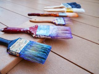 Used paint brushes drying on decking