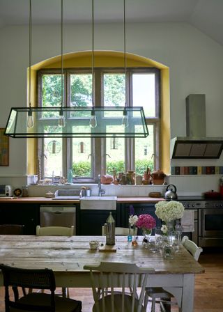 picture of a cozy kitchen in an off-white color with a pop of buttery yellow in the window trim