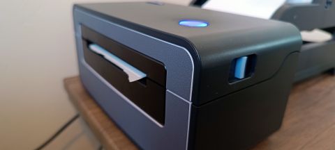 A grey Polono PL60 thermal printer sitting on a wooden table