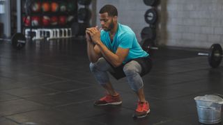 Man performs unweighted squat in gym