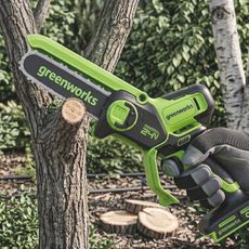 A greenworks pruning saw being used to cut a small limb off a tree