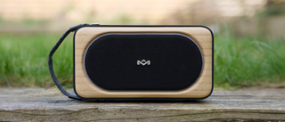 House of Marley Roots Solar Bluetooth Speaker outside on a wooden sleeper in a garden