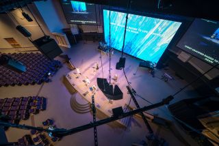 An overhead view of a church stage with d&b technologies hanging from the ceiling for enhanced sound.