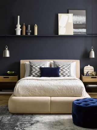 White Sunday bed in deep blue room with Turin side tables, floating shelf and leaning frames adding depth