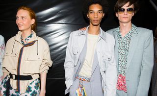 2 male models in pastel coloured clothing pose next to a female model