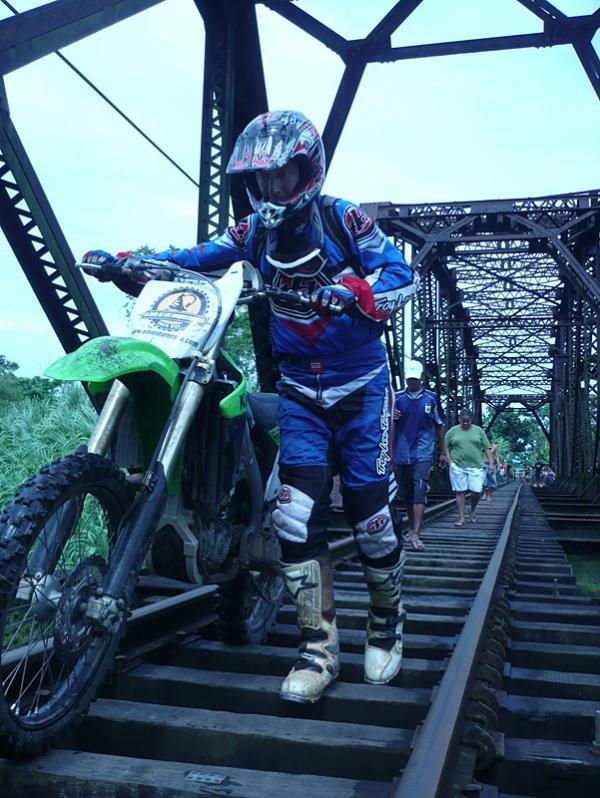 Lead moto driver pushes the bike across the bridge.
