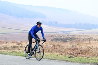 Man riding a road bike in the Peak district wearing a blue Madison DTE Isoler Thermal Long Sleeve Jacket