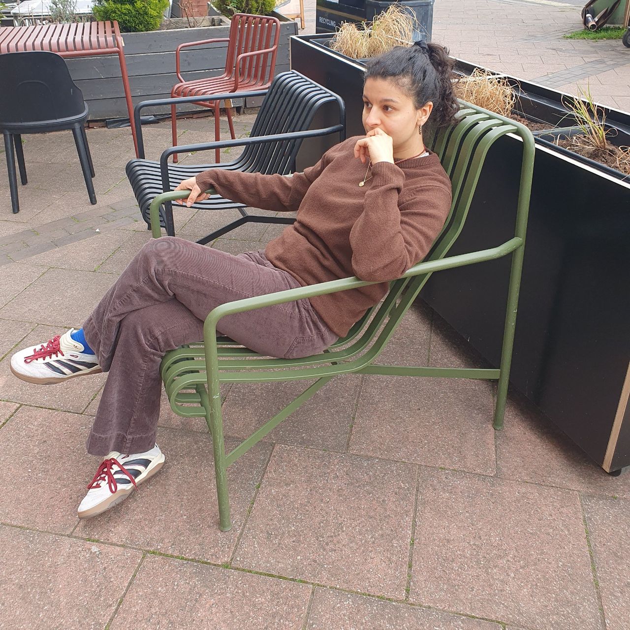 Sara sitting on a green Palissade garden chair from HAY