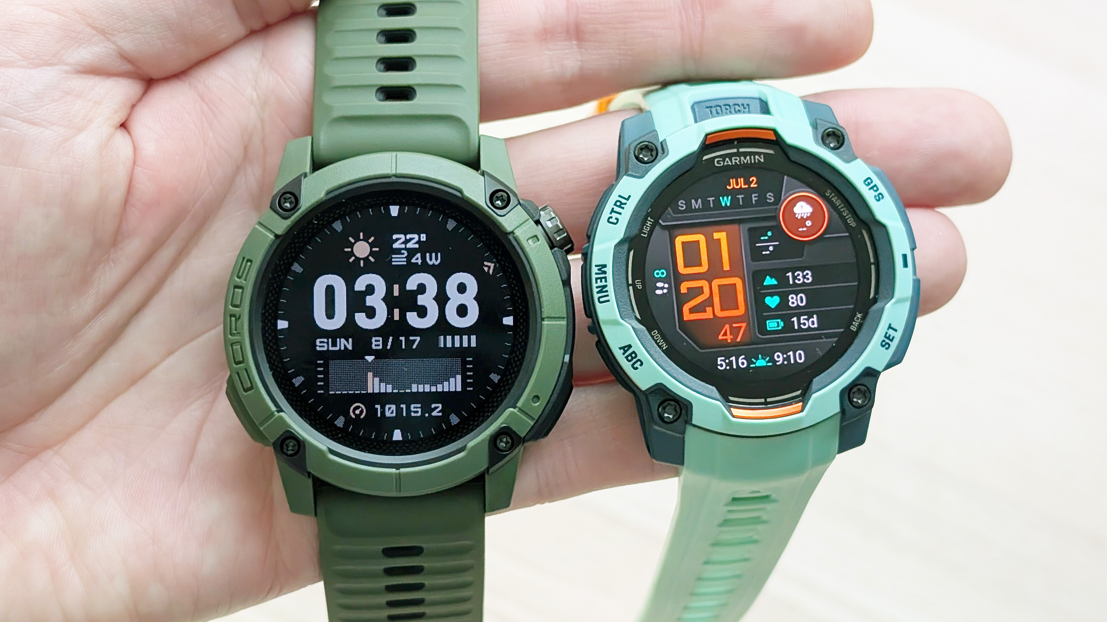Close-up of the Coros Nomad and Garmin Instinct 3 in a user's hand