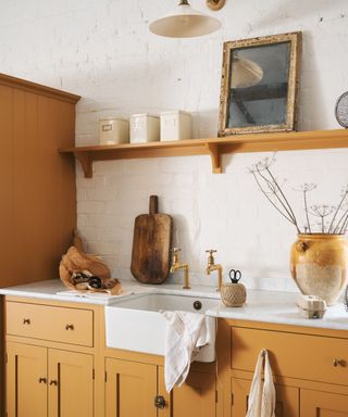 corner of kitchen with dark yellow cabinets, white brick wall and rustic decor