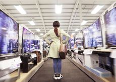 a woman standing in an aisle full of televisions