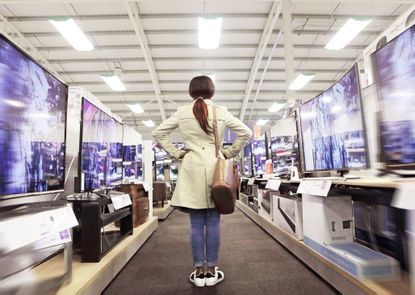 a woman standing in an aisle full of televisions