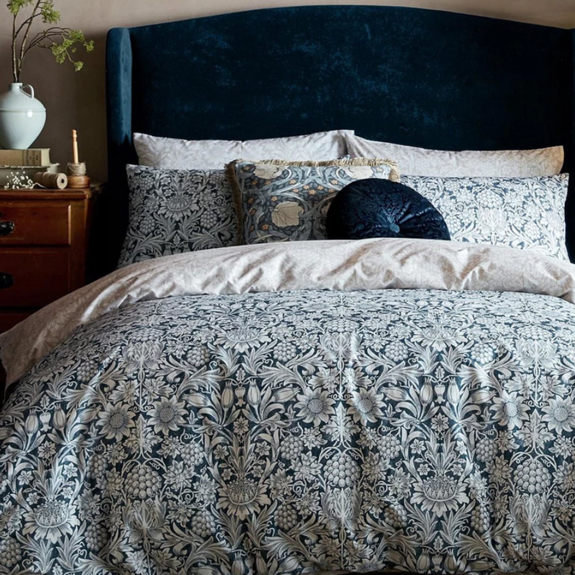 Blue Morris & Co bedding in a room with a blue velvet headboard against a taupe wall
