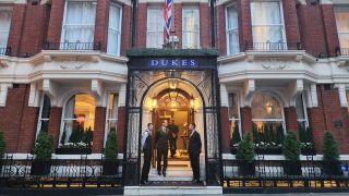 A shot of the Dukes Hotel exterior building with hotel employees standing at the door.