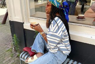 Woman in stripe t-shirt, jeans, and sandals.