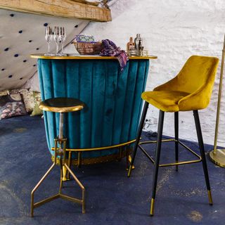 Indigo bar stand with glasses and decorative items on top next to honeycomb stools