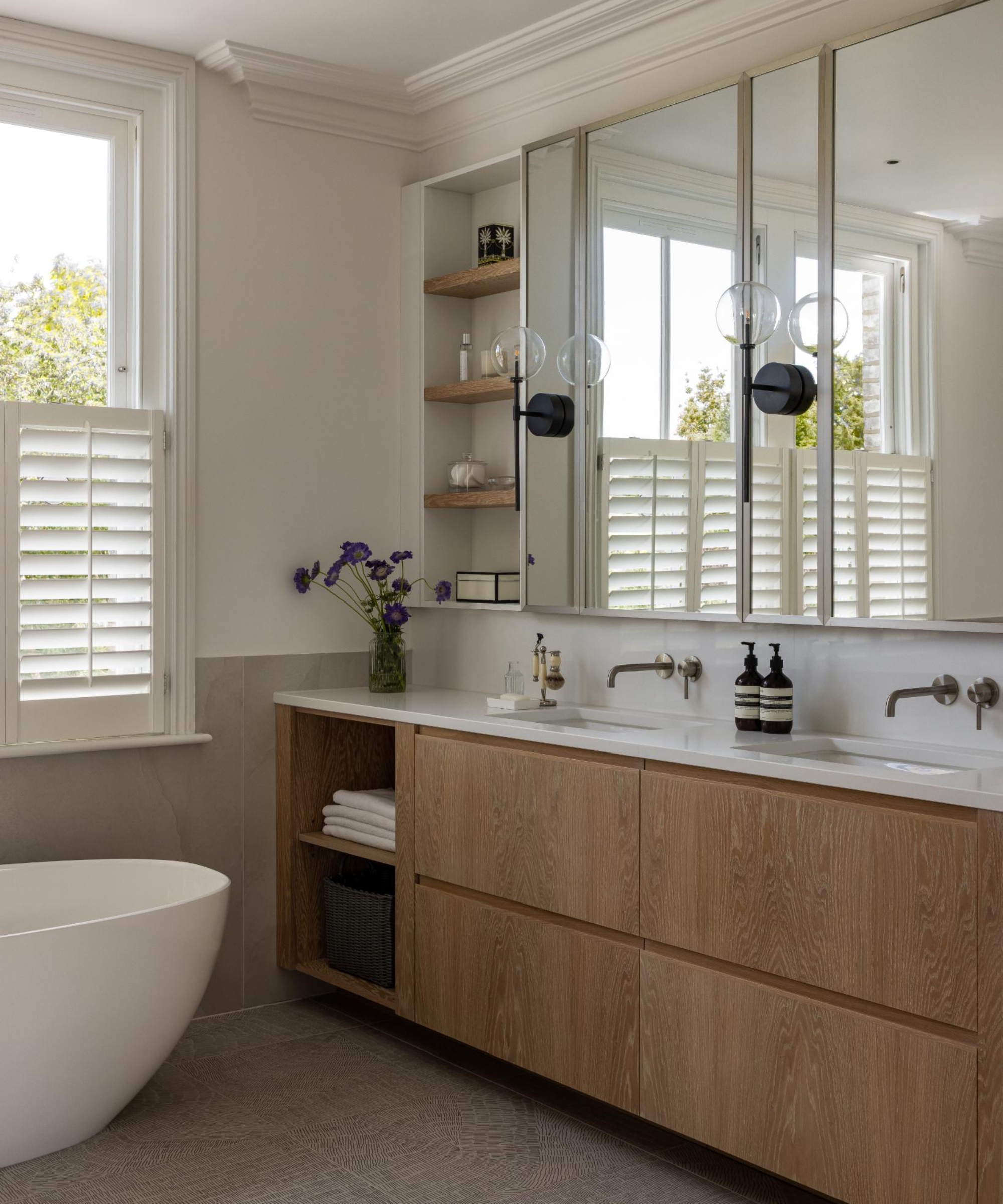 bathroom with built in wooden vanity unit with storage, double inset sinks, mirrors and storage above