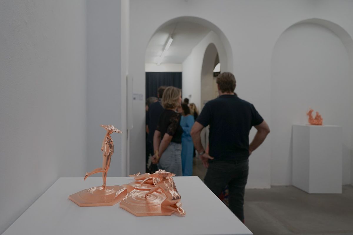 A series of golden metal sculpture and murals placed on white display tables or display walls as part of an art exhibit