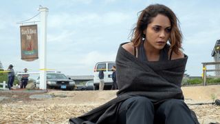 Monica Raymund sits on a beach wrapped in a blanket in a scene from "Hightown"