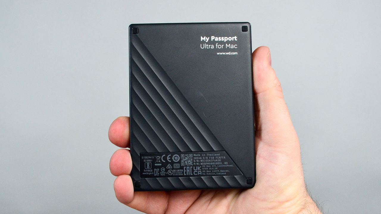 A masculine hand holding a WD My Passport Ultra for Mac