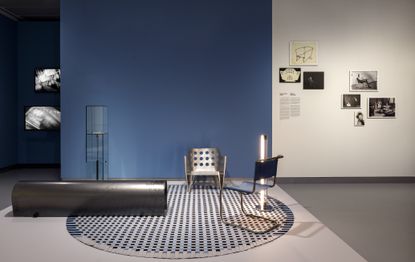 Exhibition view with contemporary pieces shown with 1920s design on round checkered rug