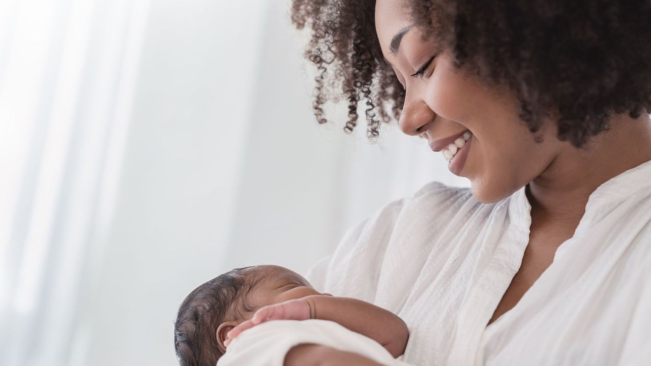 postpartum hair loss - Close up portrait of beautiful young African American mother holding newborn baby - gettyimages 1415734991