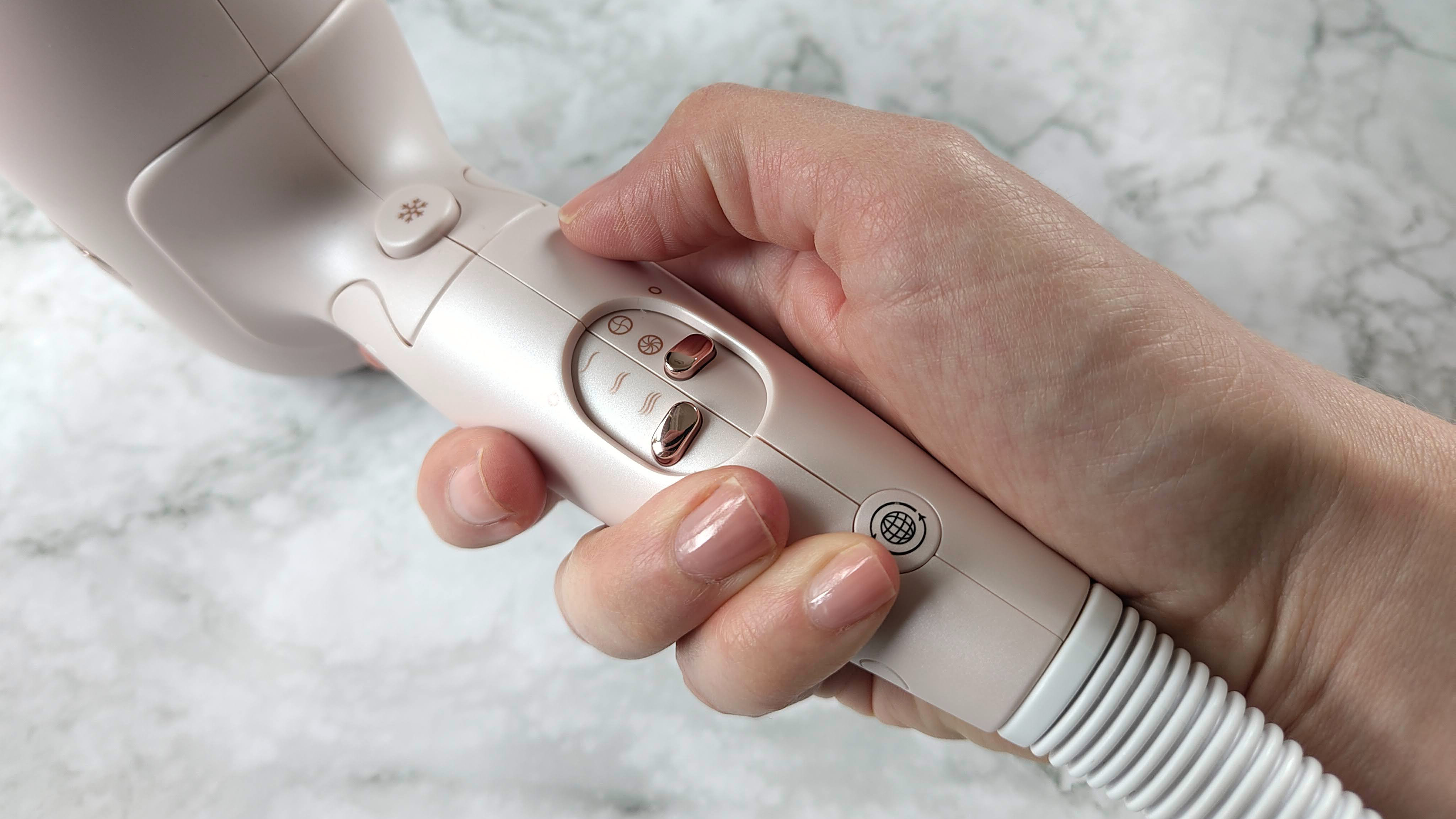 Person holding T3 Afar hair dryer, showing controls on handle