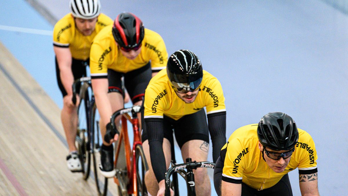 Four cyclists riding around a velodrome track