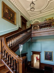 Fig 2: The main stair rises to the bedroom floor. The colour scheme and the picture hang have both been changed in the recent restoration work. Note the glass candle flutes. Radbourne House. ©Paul Highnam / Country Life