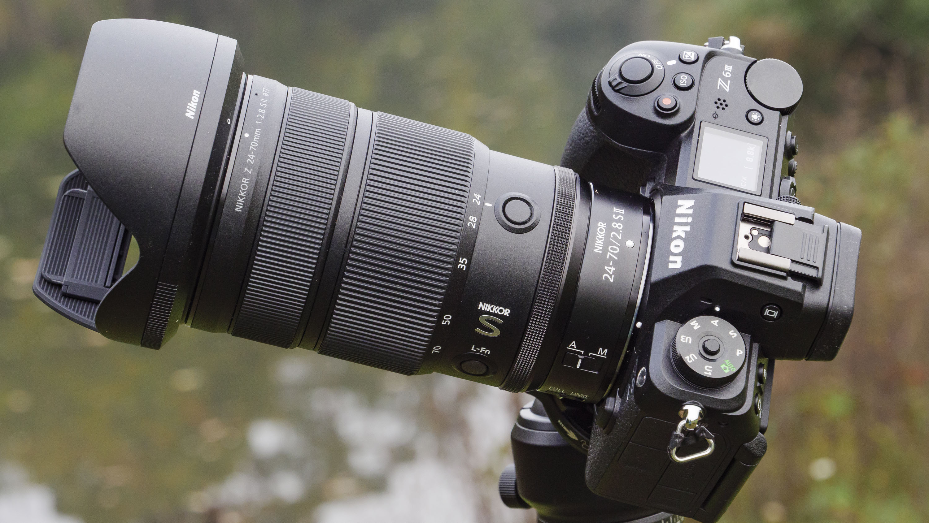 Nikon Z 24-70mm f/2.8 S II lens mounted to a tripod with autumnal lake background