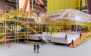 Model of the museum interior, grey floor, yellow metal scaffolding, white platforms, steps, model people, brick walls, orange walkway slopes, clear plastic sheet covering part of the model roof
