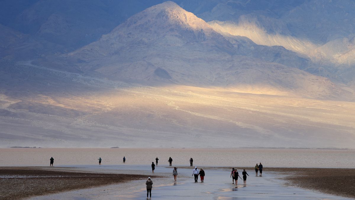 ourists enjoy the rare opportunity to walk in water as they visit Badwater Basin, the normally driest place in the US