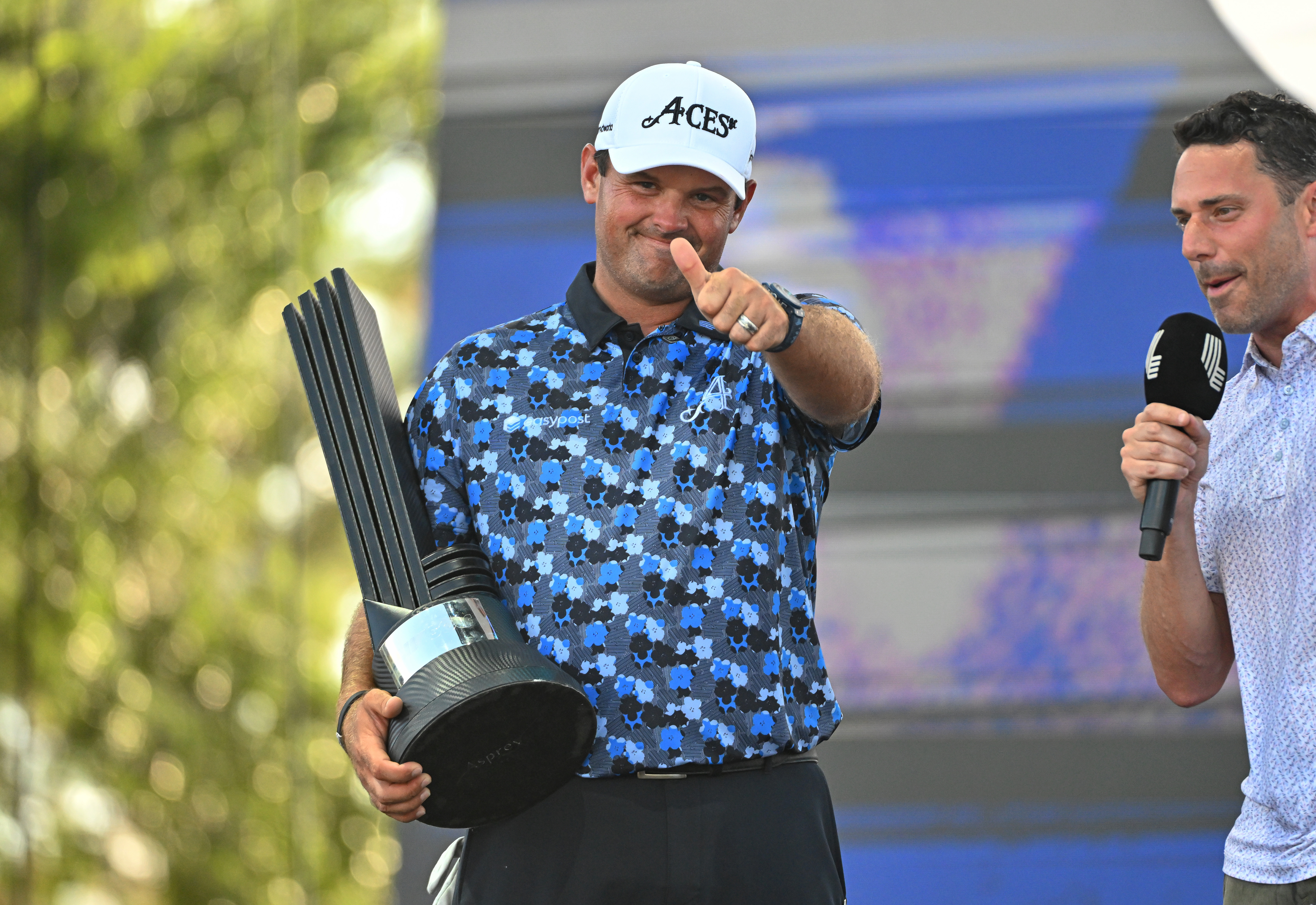 Patrick Reed holds the LIV Golf Dallas trophy and puts his thumbs up to the crowd