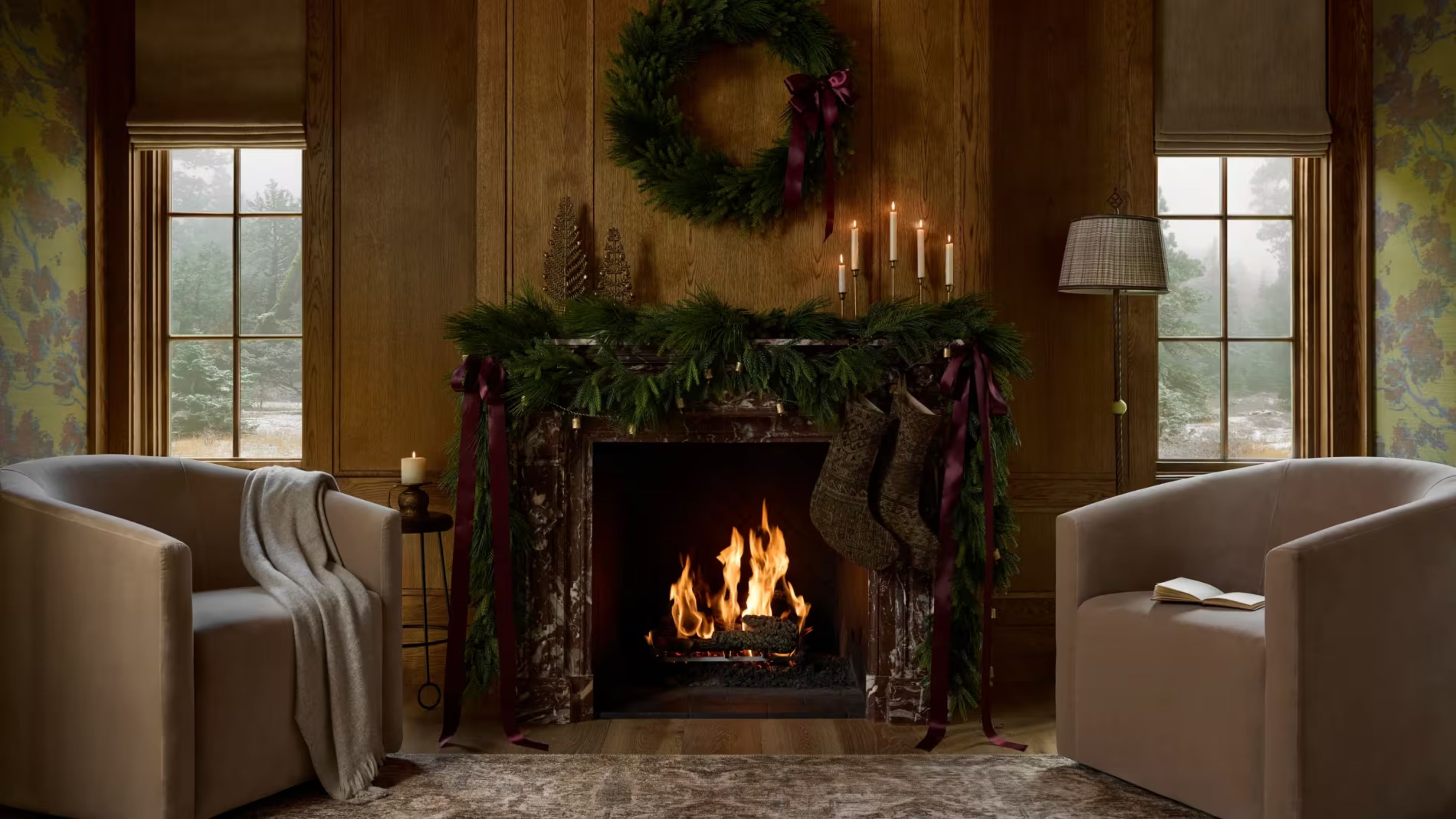 Cozy, festive living room featuring a roaring fireplace styled with garland and a Christmas wreath overhead. Two sitting chairs flank the wood-paneled scene.