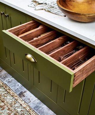 a green kitchen with a drawer open
