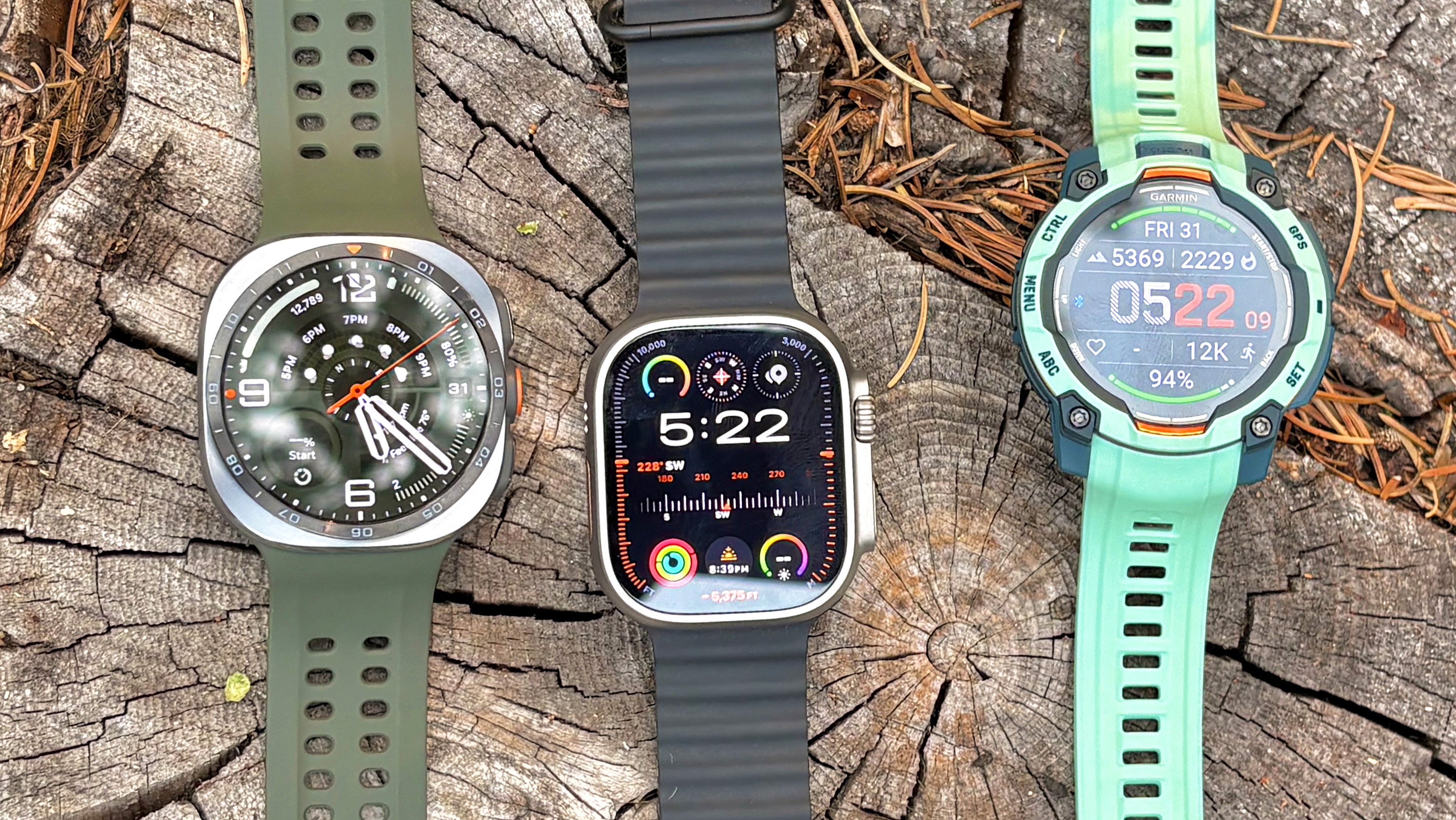 Close-up of the Samsung Galaxy Watch Ultra 2, Apple Watch Ultra 3 and Garmin Instinct 3 in nature
