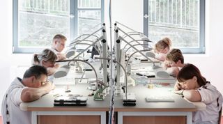 Watchmakers at their workstations assembling movements